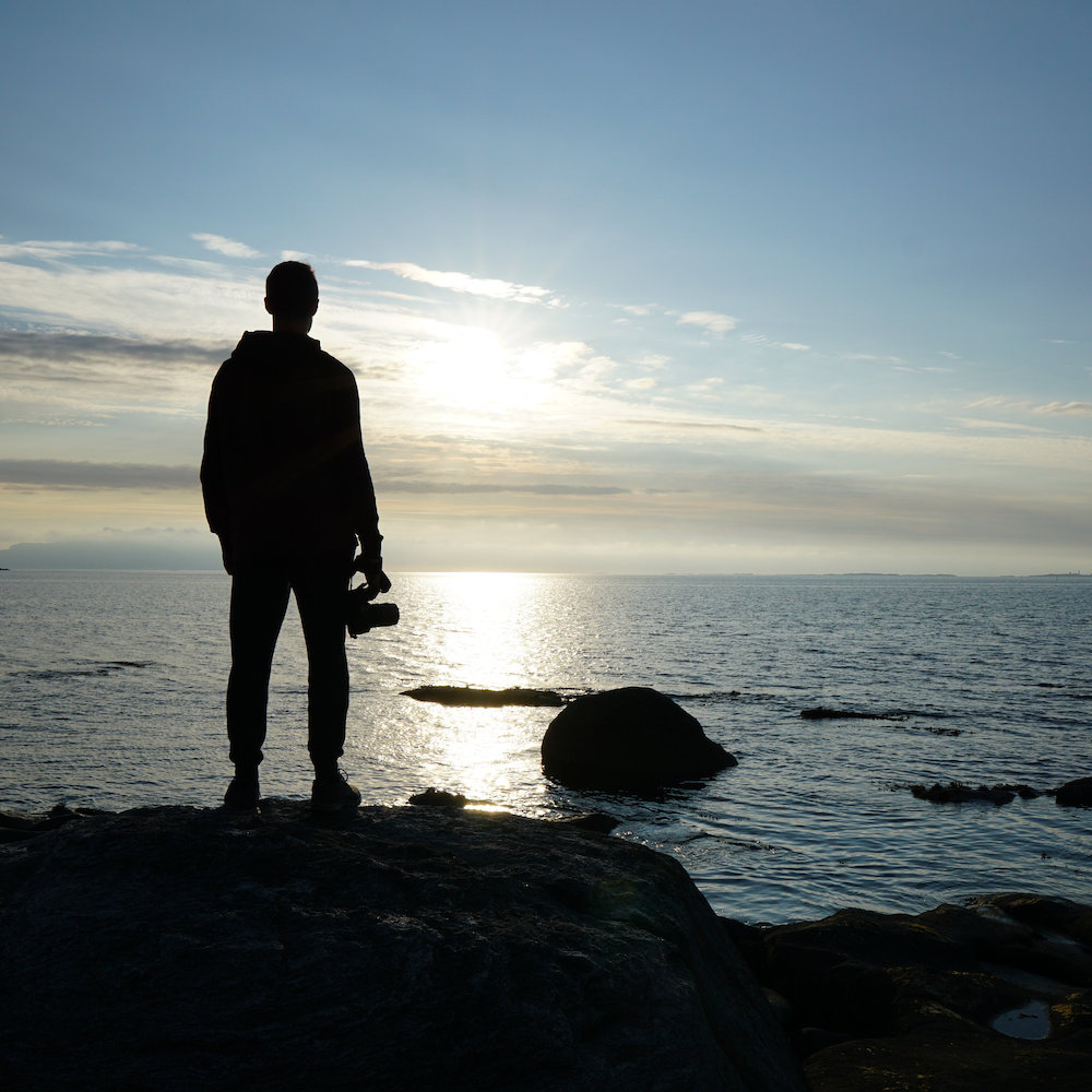 me as a silhouette standing on top of a rock looking into the ocean